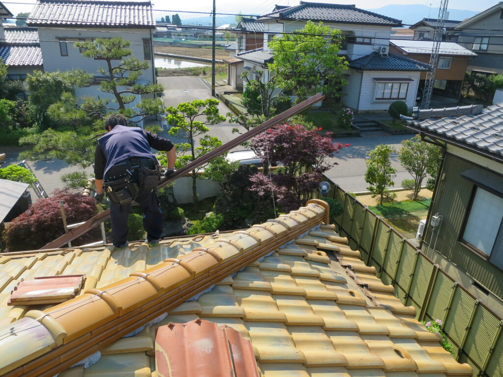 瓦をめくった状態で見える樋金物の交換作業中